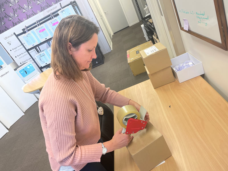 Fay using cellotape role to pack order